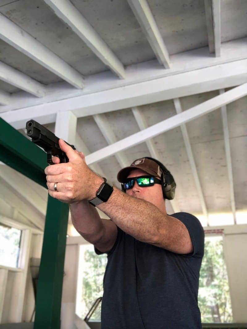 Josh Malcolm shooting a Sig Sauer P226 at an indoor range, wearing eye and ear protection